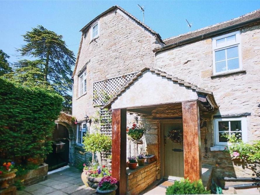 een stenen huis met een deur met potplanten erop bij Pike Cottage in Stow on the Wold