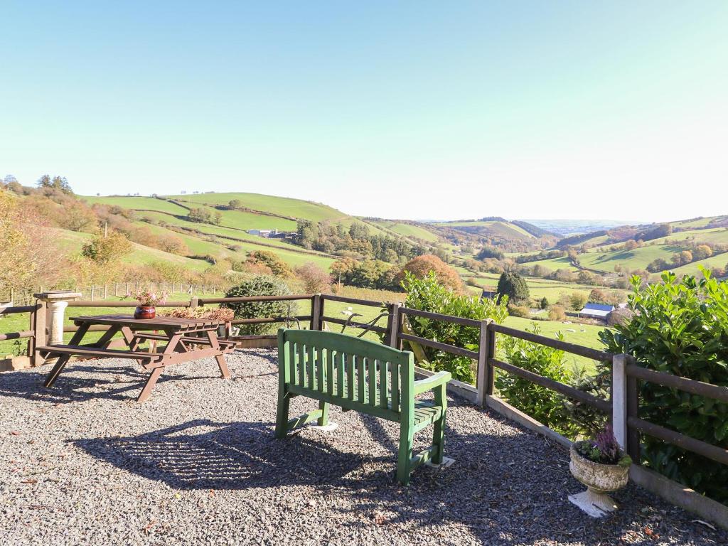 a green bench sitting next to a wooden fence at Cedar Cottage in Llanidloes