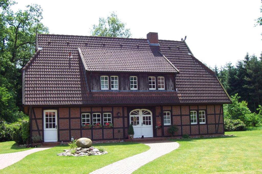 Casa marrón con puertas blancas y patio de césped en Theeshof, en Soltau