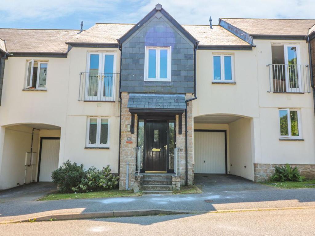 a large white house with a driveway at Strawberry Cottage in Penryn