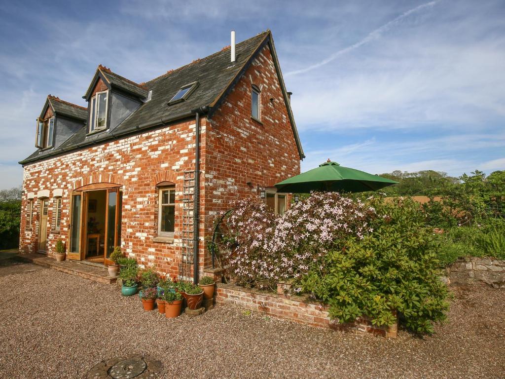 a brick house with an umbrella and some plants at The Coach House in Exmouth
