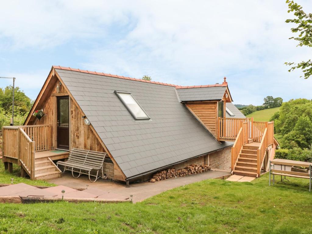 a log cabin with a deck and a roof at The Lookout in Llangarren