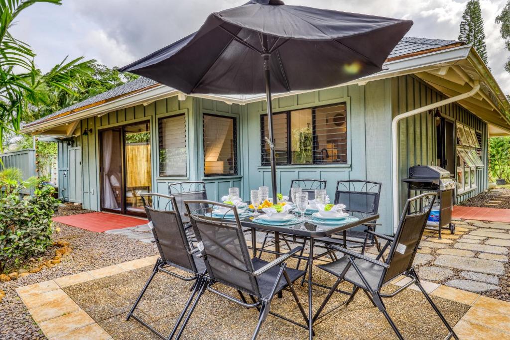 a table with an umbrella in front of a house at Sea Turtle Cottage in Princeville