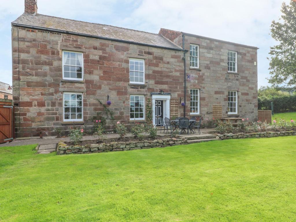 a brick house with a lawn in front of it at Godscroft Hall in Frodsham