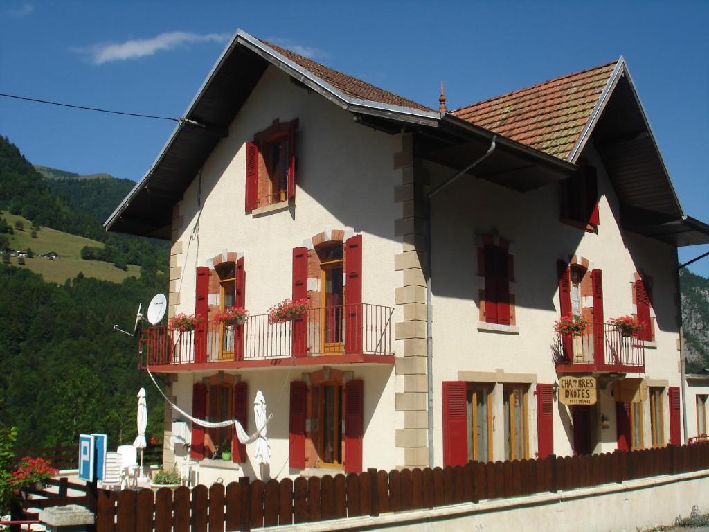 uma casa branca com persianas vermelhas e uma cerca em L'Horizon des Alpes em Le Petit-Bornand-lès-Glières