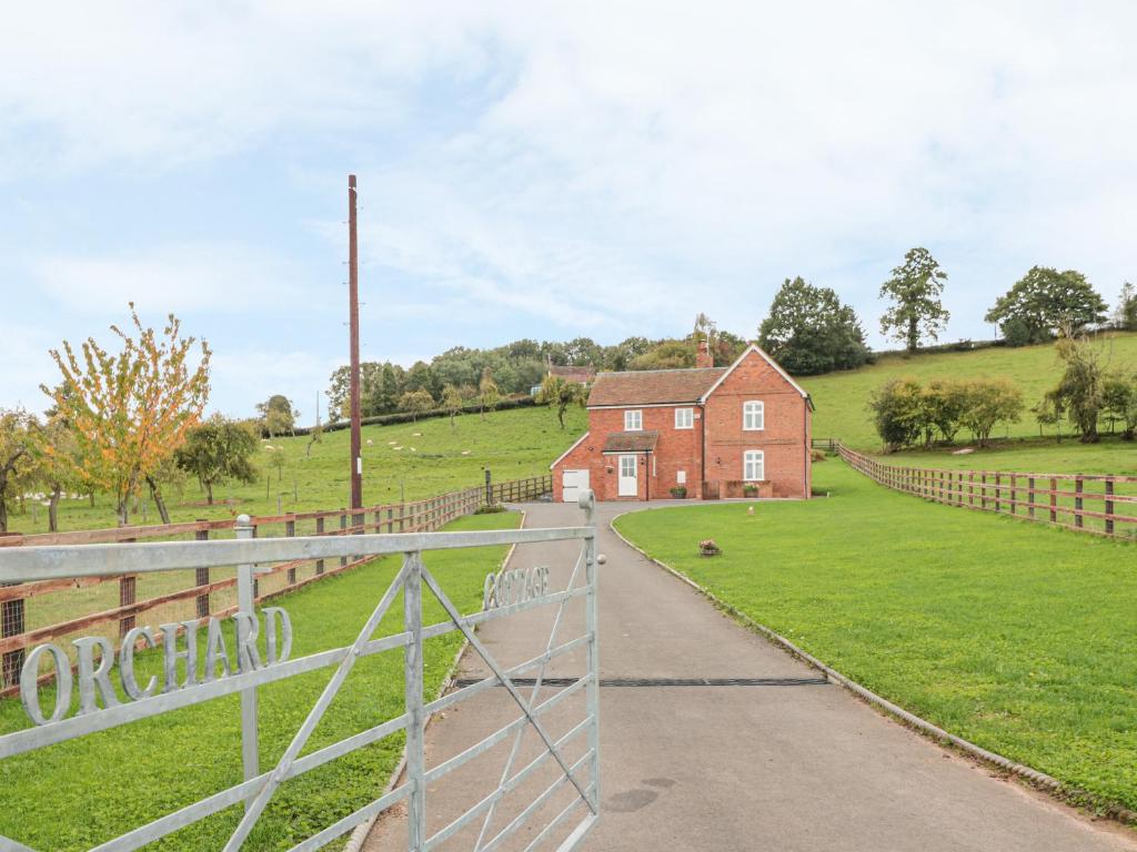 a fence in front of a red brick house at Orchard Cottage in Tenbury