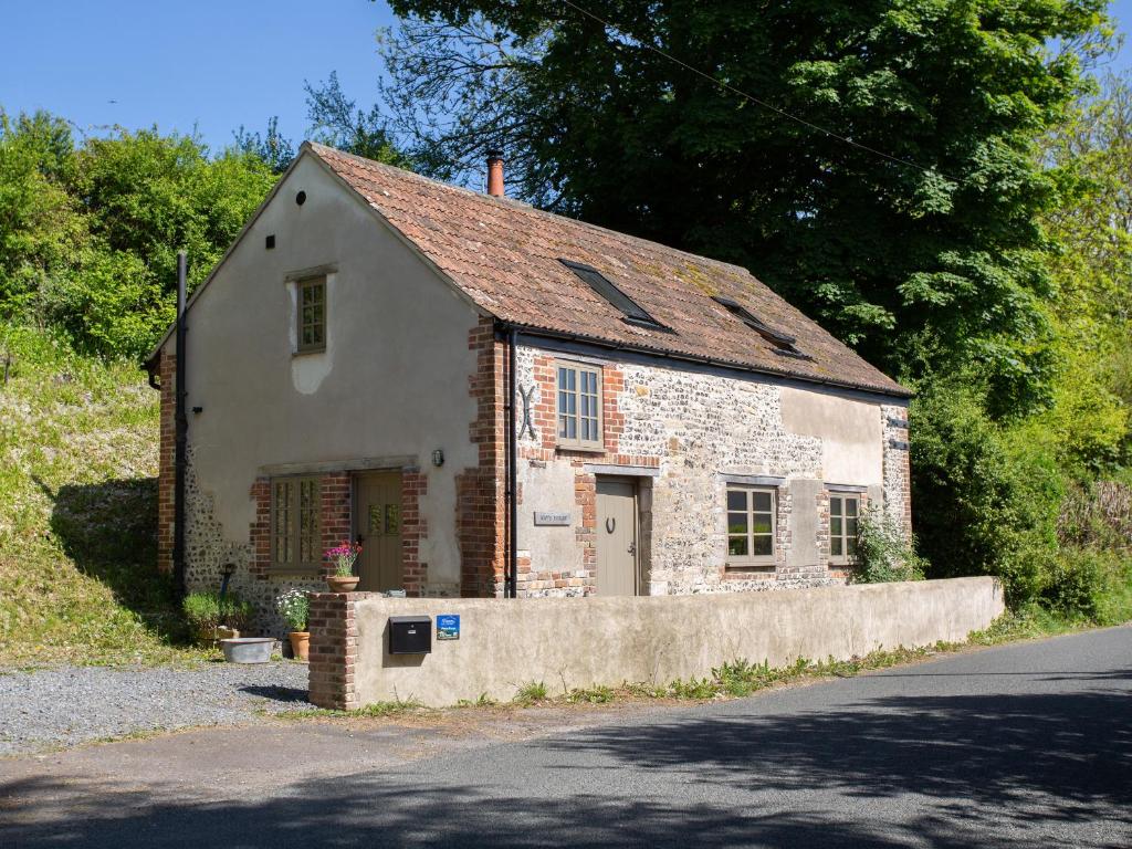 uma pequena casa de pedra ao lado de uma estrada em Way's Forge em Dorchester