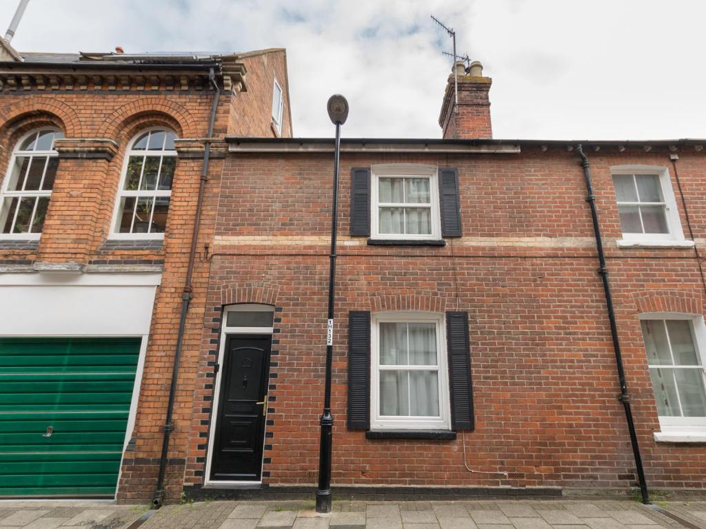 ein rotes Backsteingebäude mit grüner Tür in der Unterkunft Harbour Catch Cottage in Weymouth