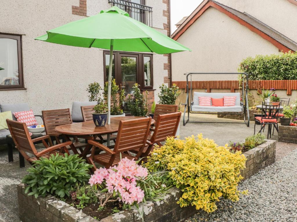 a patio with a table and chairs and a green umbrella at Bwlch Y Gwynt Bach in Llangefni
