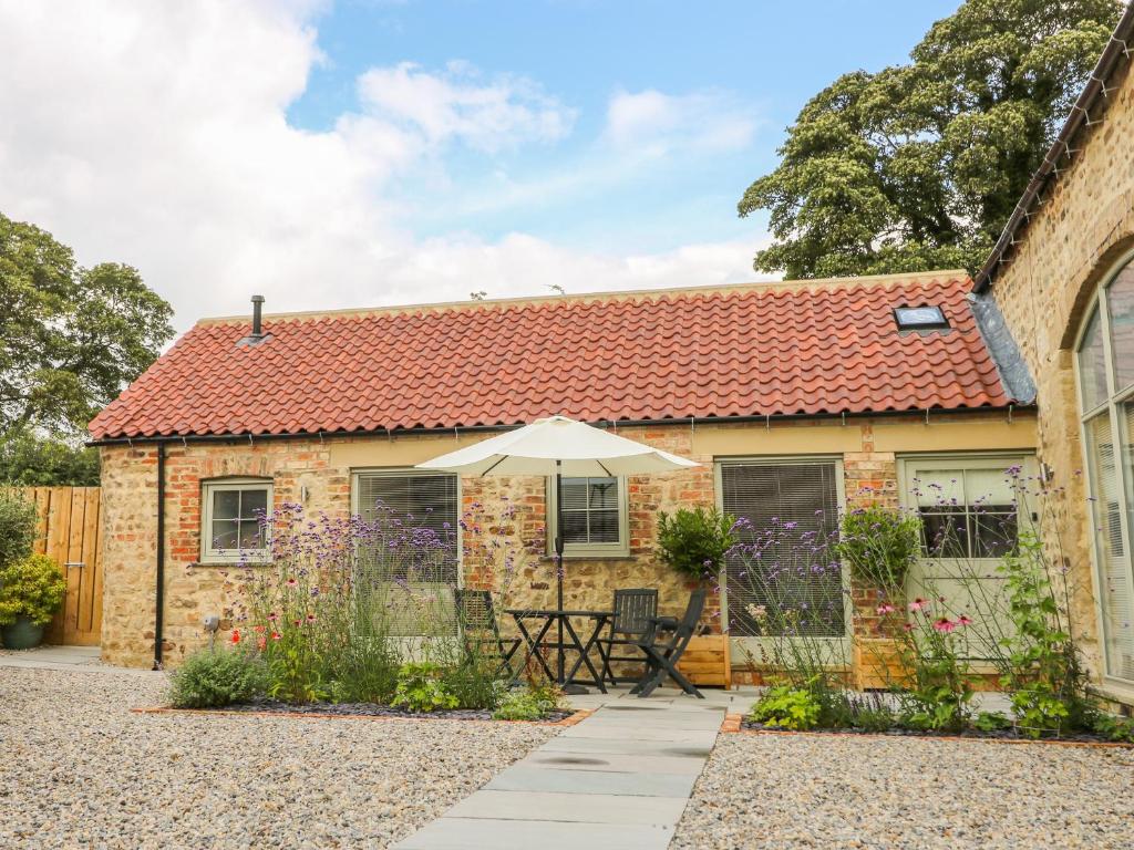 a brick house with an umbrella in front of it at Wallerthwaite Barn Cottage in Harrogate