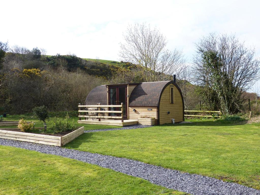 a barn with a black roof on a grass field at Gelert Pod in Tremeirchion