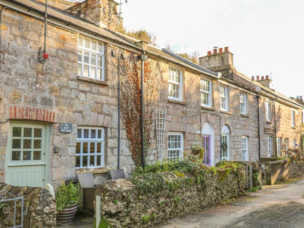 an old stone building with a bench in front of it at May Cottage in Pentewan