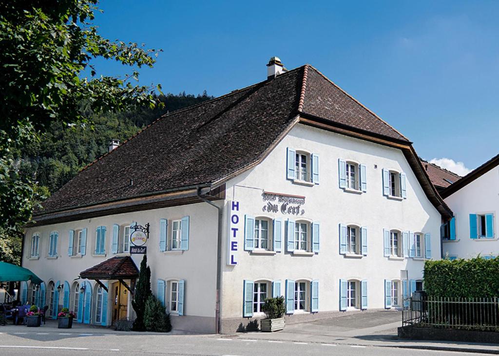 ein großes weißes Gebäude mit braunem Dach in der Unterkunft Hôtel-Restaurant du Cerf in Sonceboz