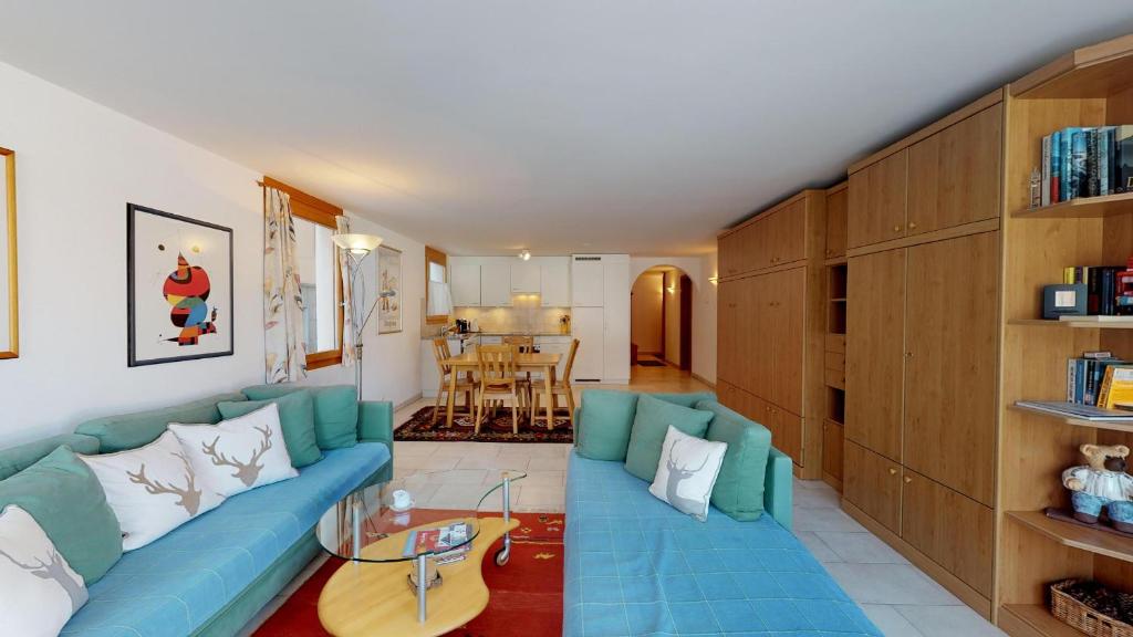 Una sala de estar con un sofá azul y una mesa. en Splendura 2A, en Silvaplana