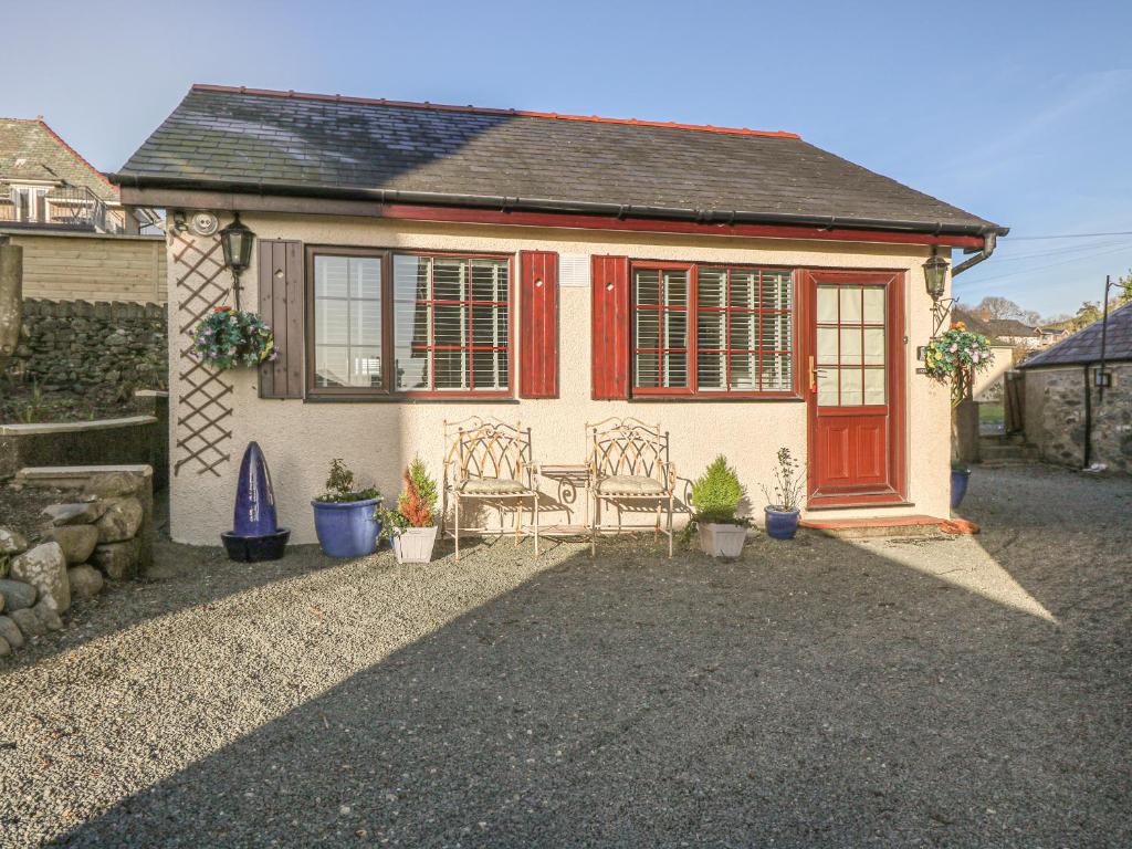 a small house with a red door and two chairs at Holly Cottage in Criccieth