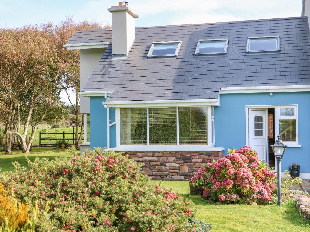 uma casa azul com flores num quintal em The Blue Annex em Tralee