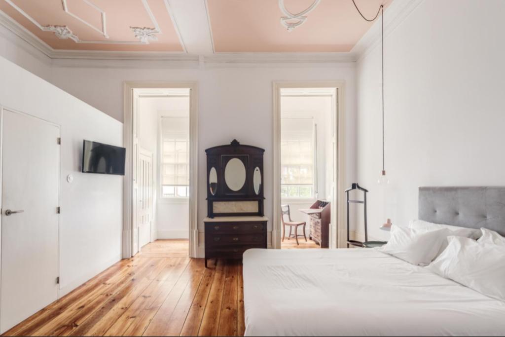ein weißes Schlafzimmer mit einem Bett und einem Spiegel in der Unterkunft O da Joana in Porto