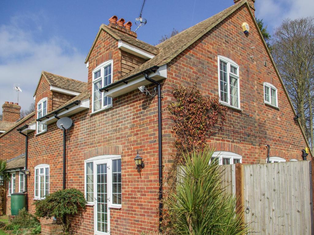 a red brick house with white windows and a fence at Knights Cottage in Maidstone