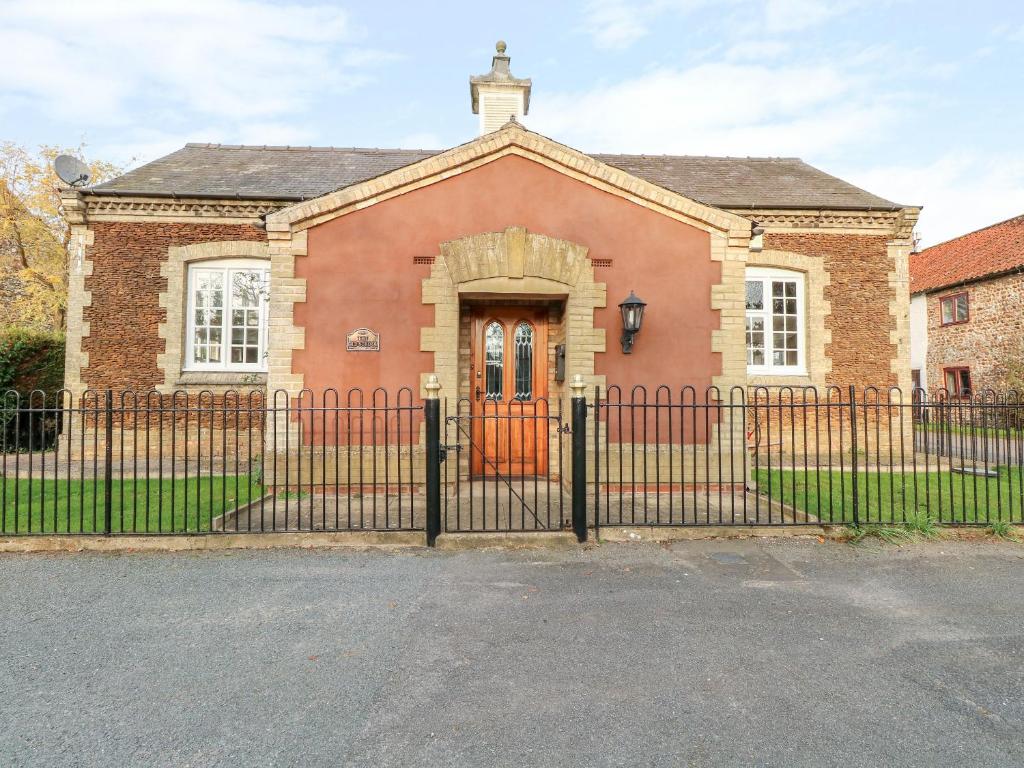 a red brick house with a black fence at The Old School in Wereham