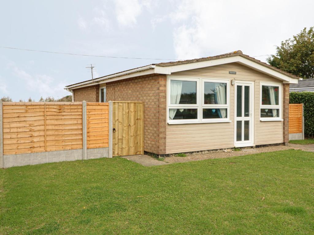 a small house with a fence in a yard at Moggs Retreat in Skegness