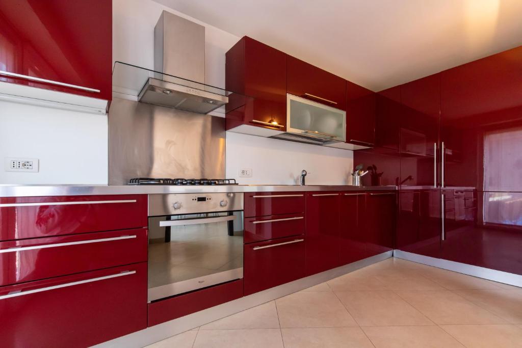uma cozinha com armários vermelhos e um forno com placa de fogão em Diamond Rooftop by Babylon Stay em Nápoles