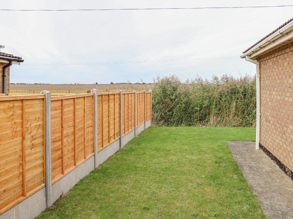 a wooden fence in a yard with grass at Moggs Retreat in Skegness