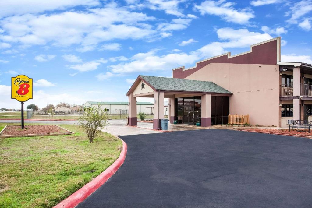 a building with a sign next to a driveway at Super 8 by Wyndham Giddings in Giddings