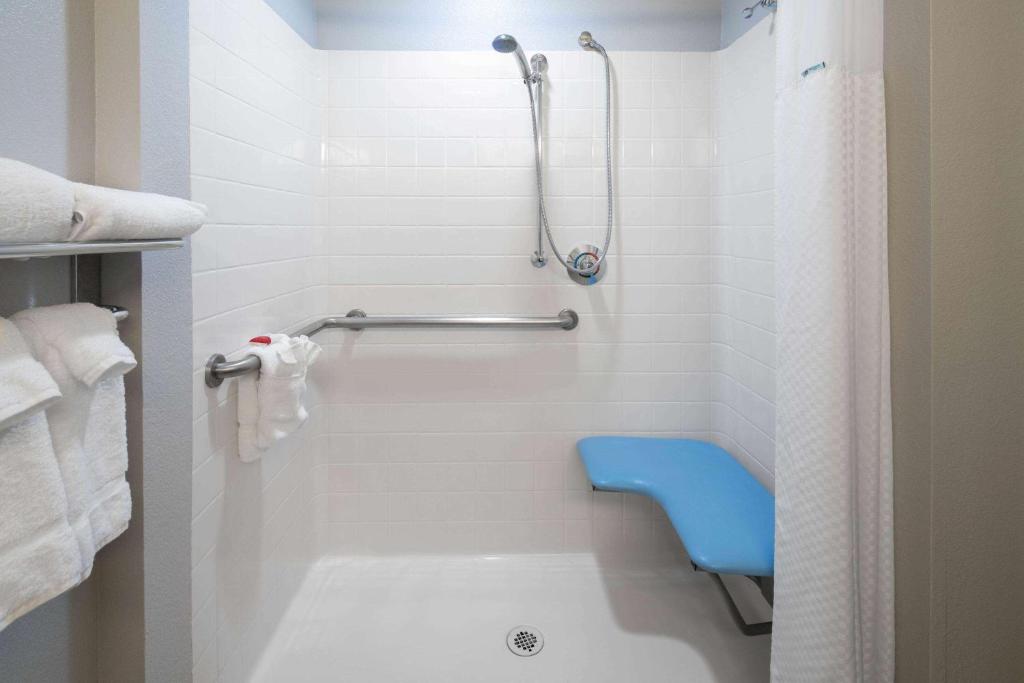 baño con ducha y asiento azul en Baymont by Wyndham Las Vegas South Strip en Las Vegas