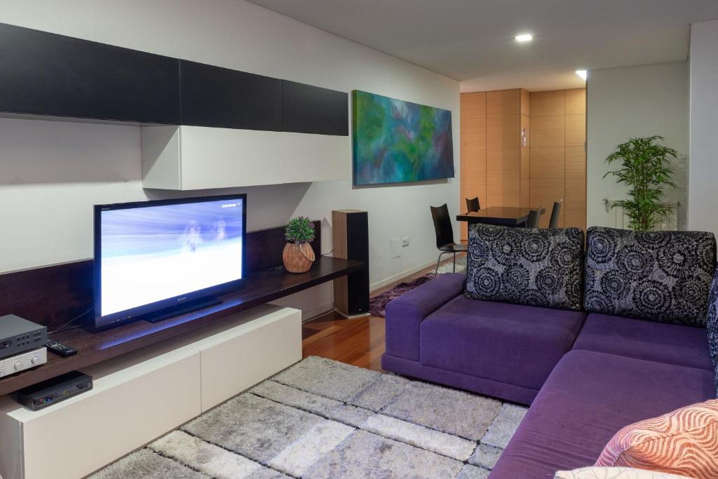 a living room with a purple couch and a tv at Porto Dragão in Porto