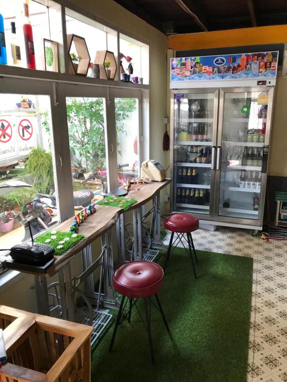 a restaurant with two bar stools and a refrigerator at GATE 14 Inn in Nakhon Phanom