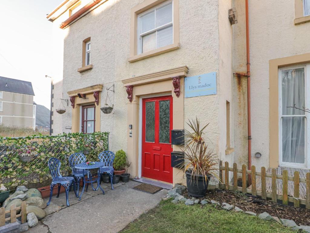a red door on a house with chairs and a table at Llys Madoc, First Floor Flat in Penmaen-mawr