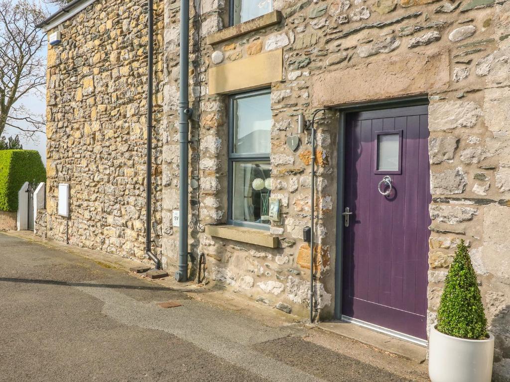 una puerta púrpura en el lateral de un edificio de piedra en Bank End Cottage, en Carnforth
