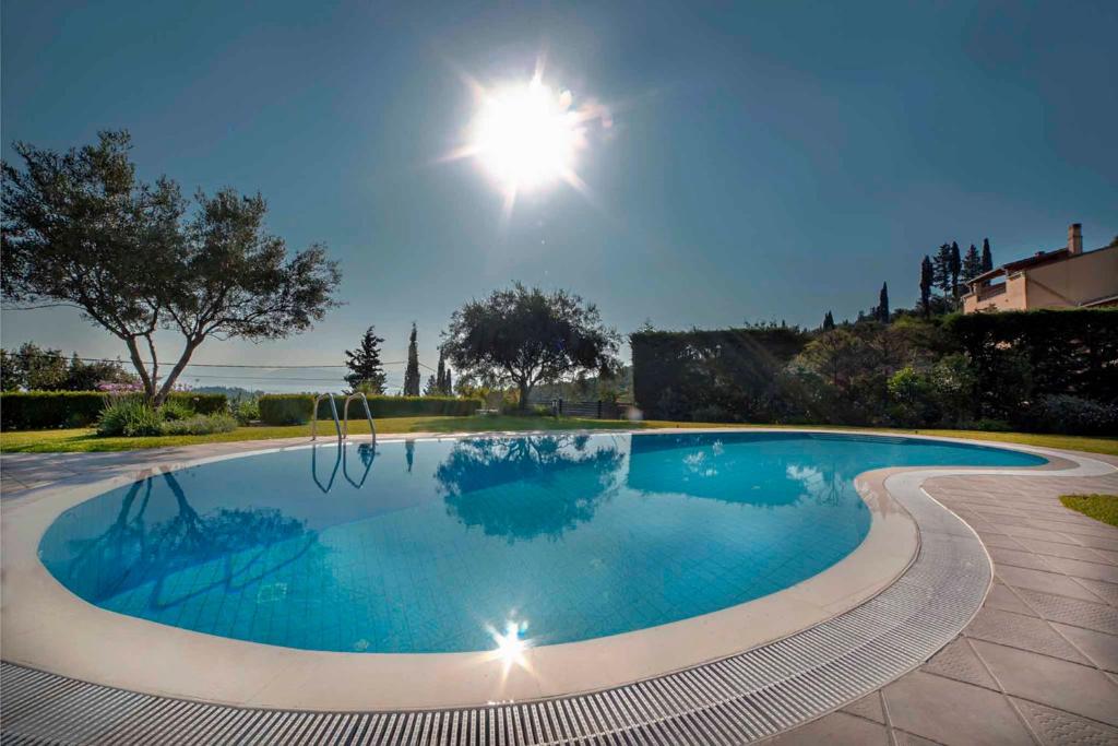 a swimming pool with the sun shining above it at Marina View Luxury Home in Gouvia