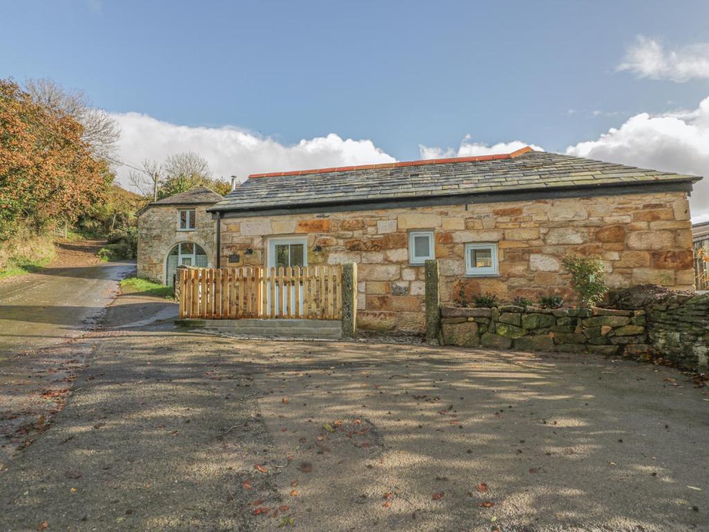 a stone house with a wooden gate and a driveway at The Bull Pen in St Austell