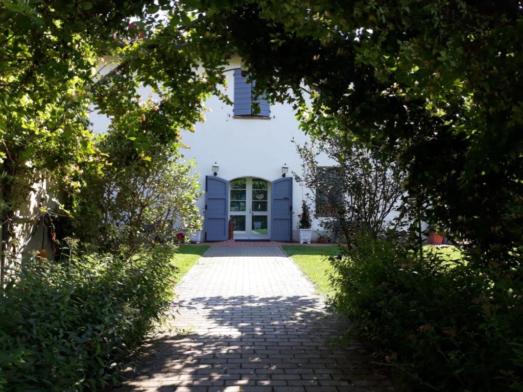 a pathway leading to a white house with a door at Agriturismo Fattoria Corte Roeli in Malalbergo