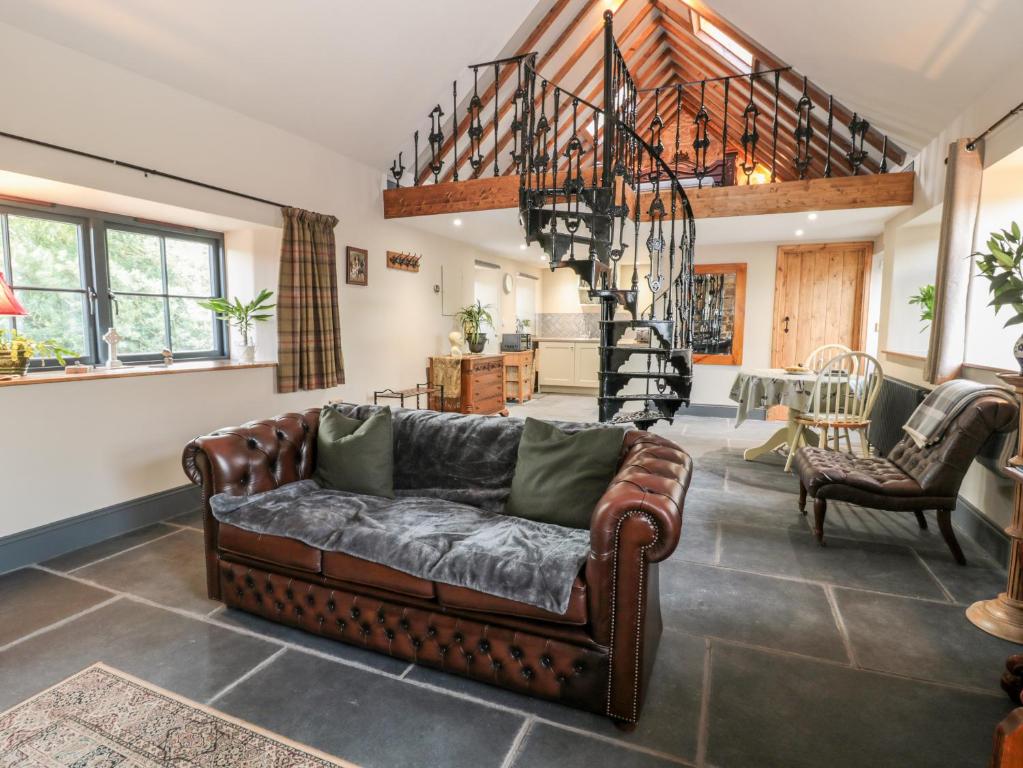a living room with a couch and a staircase at Stable Cottage in Berwick-Upon-Tweed