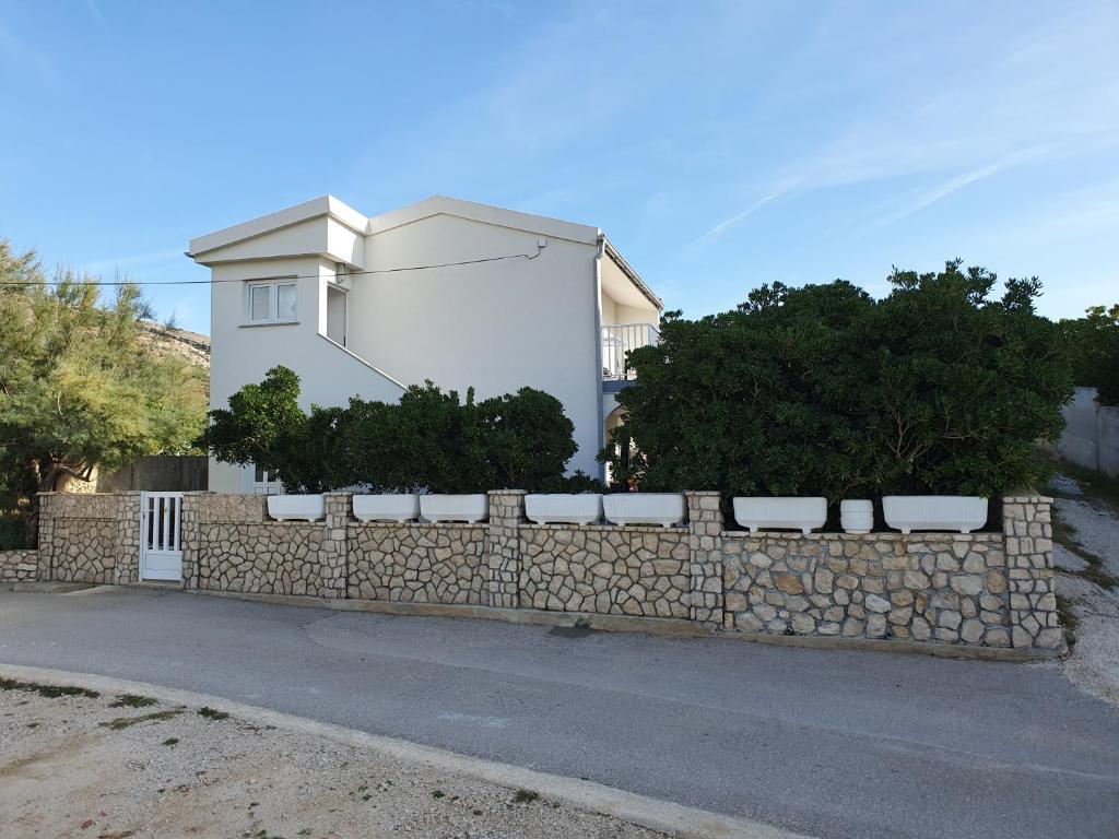 a stone retaining wall in front of a house at Apartments Tramontana in Pag