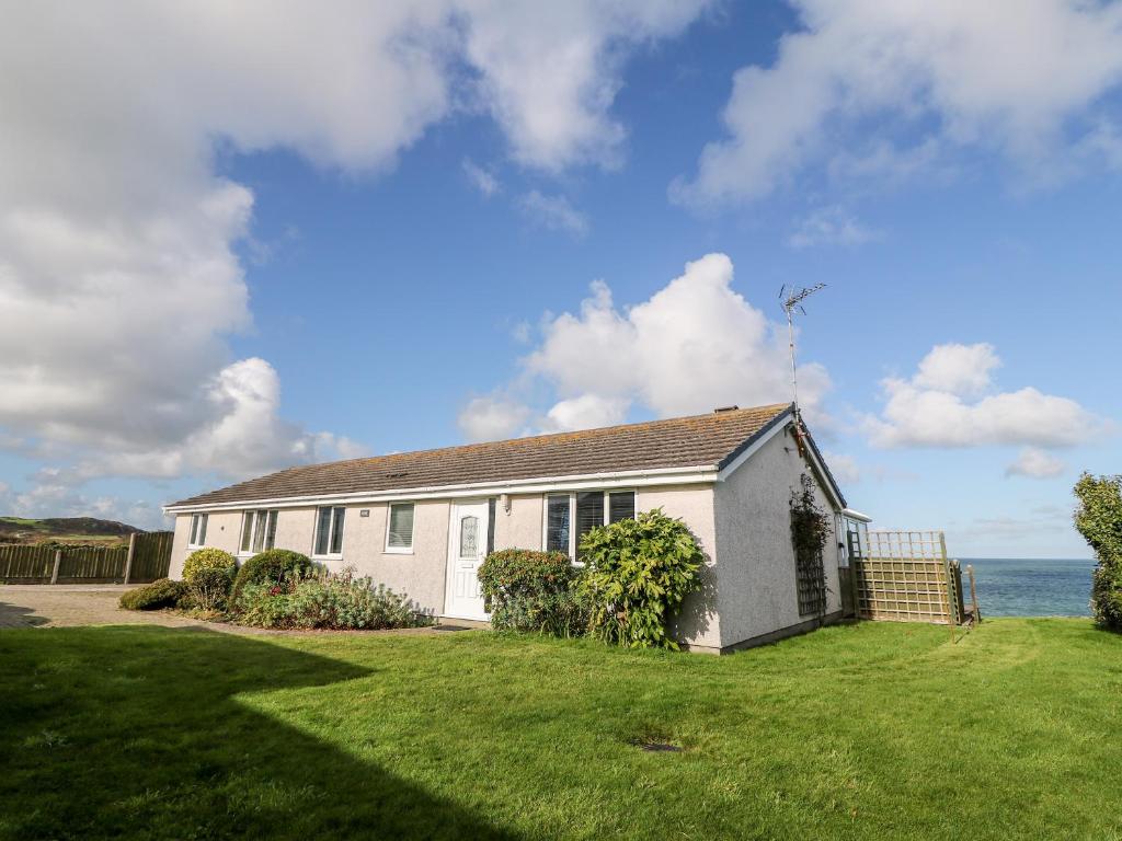 a white house with the ocean in the background at Golygfa Ynys Island View in Amlwch