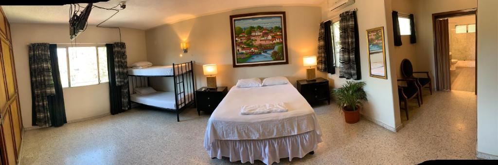 a bedroom with a white bed and a room with a desk at Palmira Hostel in Tegucigalpa