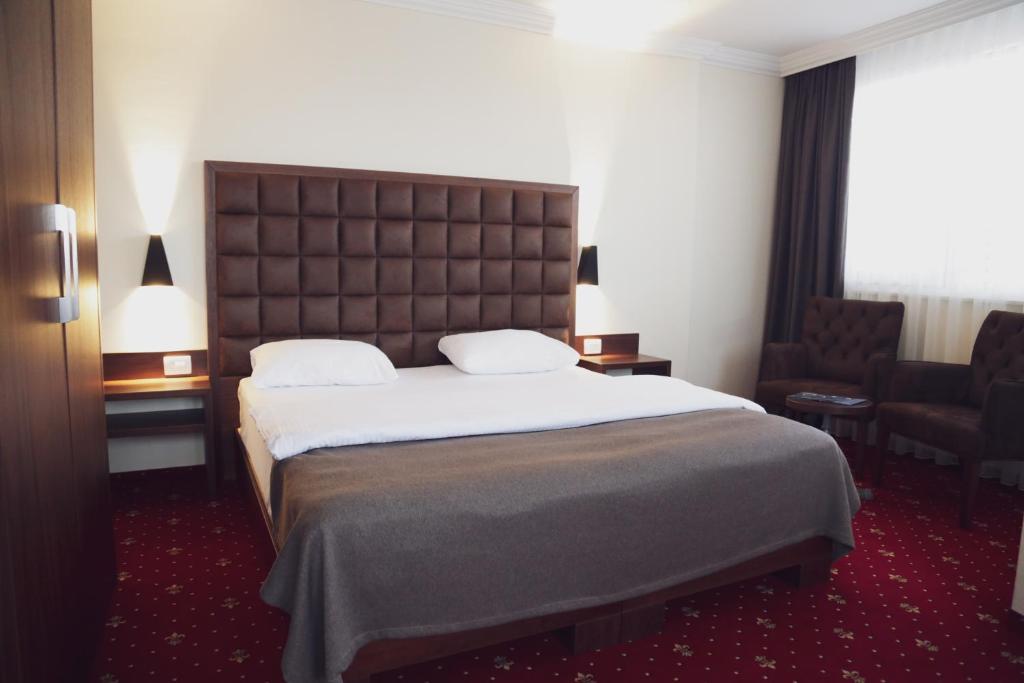 una habitación de hotel con una cama grande y una silla en City Hotel en Prizren