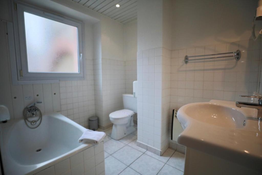 a bathroom with a tub and a toilet and a sink at Hotel Wilson Square in Toulouse