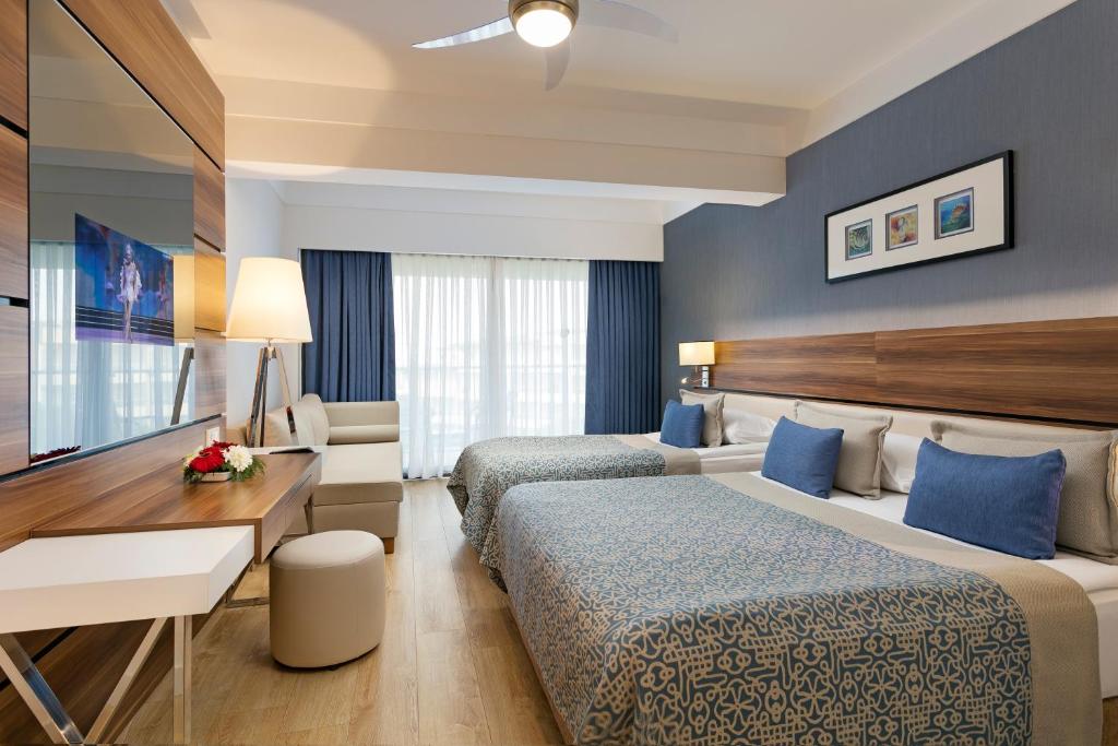 a hotel room with two beds and a desk at Limak Atlantis Deluxe Hotel Belek in Belek