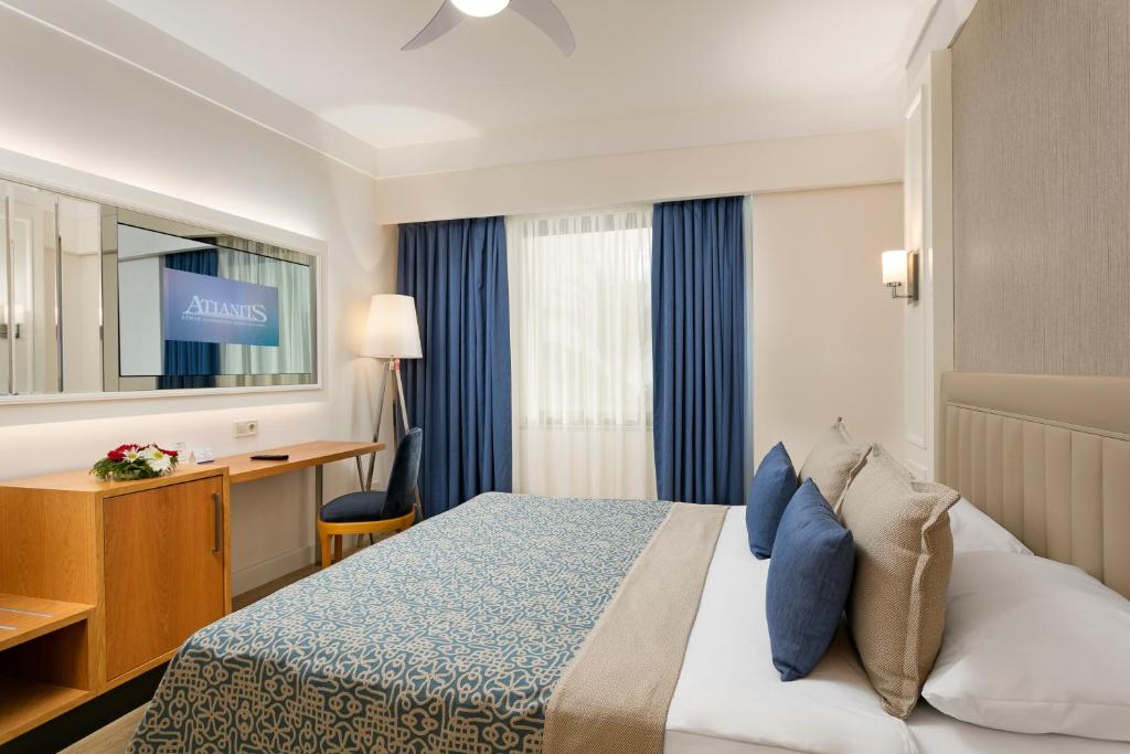 a hotel room with a bed and a desk and a mirror at Limak Atlantis Deluxe Hotel Belek in Belek