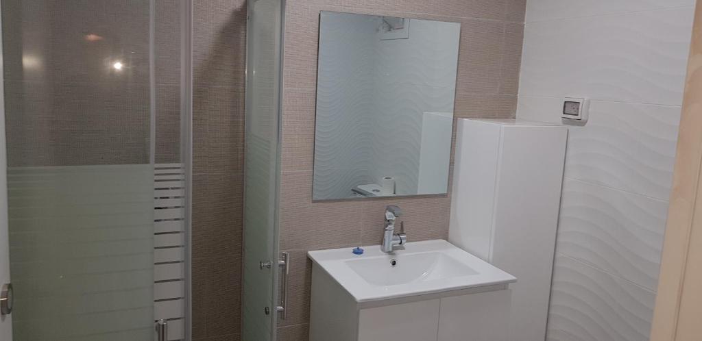 a bathroom with a sink and a mirror and a shower at Neviot in Eilat