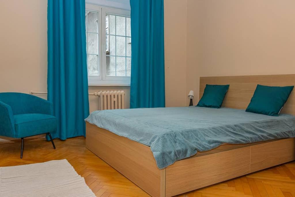- une chambre avec un lit doté de rideaux bleus et d'une chaise dans l'établissement Apartament Brama Chlebnicka, à Gdańsk