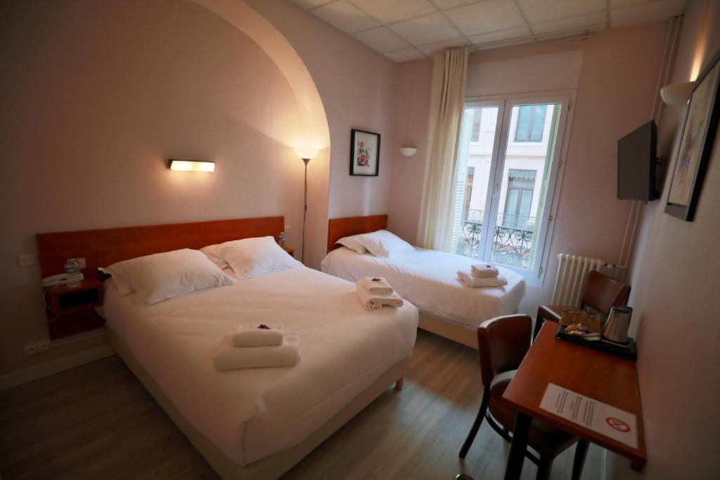 a bedroom with two beds and a desk and a window at Hotel Wilson Square in Toulouse