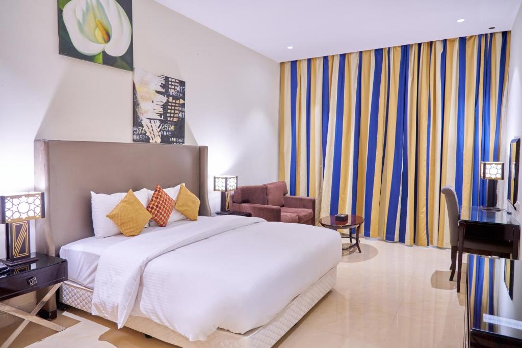 um quarto com uma grande cama branca e uma cadeira em City Stay Grand Hotel Apartments - Al Barsha em Dubai