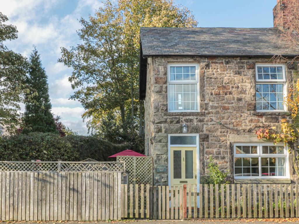 an old stone house with a wooden fence at Wordsworth Cottage West in Morpeth