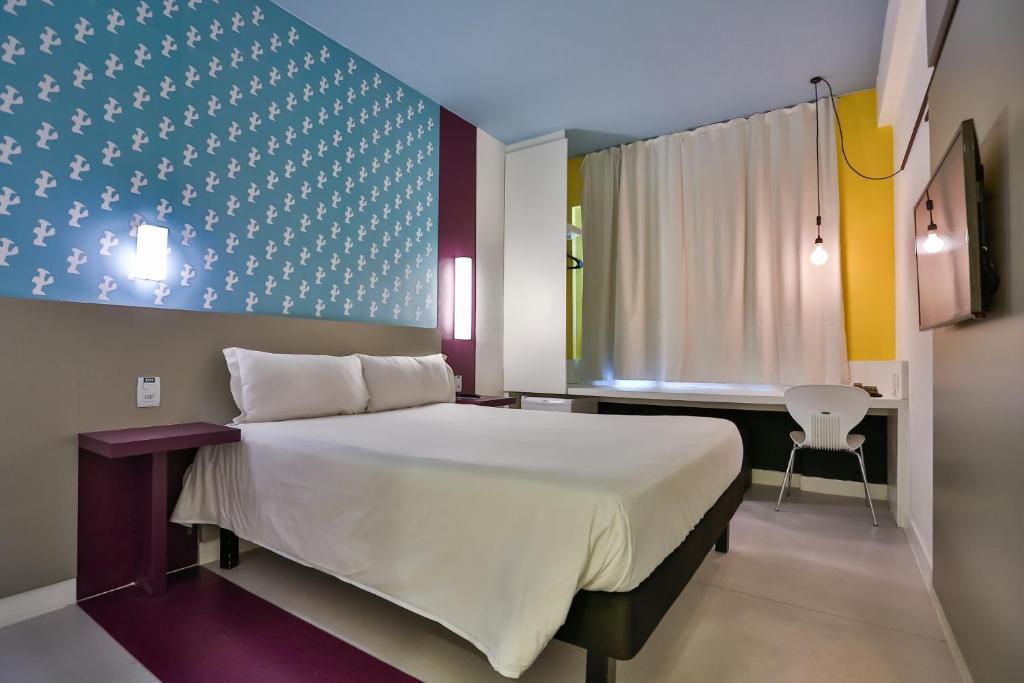 een slaapkamer met een bed, een bureau en een raam bij Nobile Inn Pampulha in Belo Horizonte