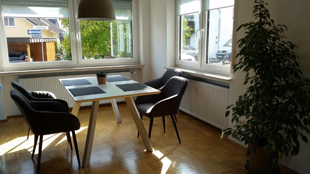 une table et des chaises dans une pièce avec fenêtres dans l'établissement Neue Fewo in perfekter Lage (Limburg a. d. Lahn), à Limburg an der Lahn